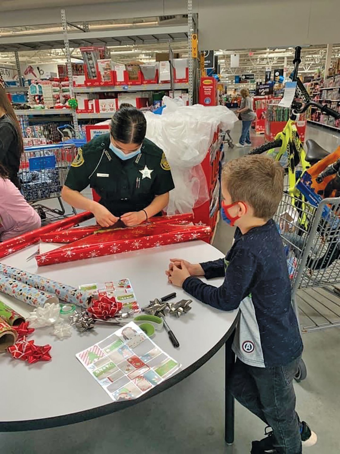 A child waits patiently while a HCSO deputy wraps the gift he picked out during the Shop with the Sheriffs event.
